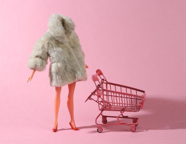 A doll with a fur coat and a shopping cart next to it