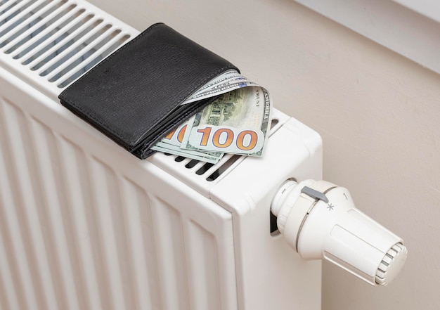 Dollar banknotes on central heating radiator the concept of expensive heating costs