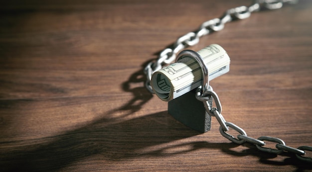 Dollar banknotes locked with chains and padlock