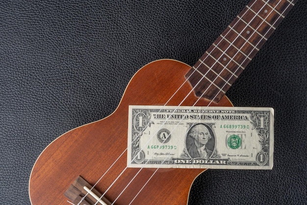 A dollar bill is stuck into a ukulele.