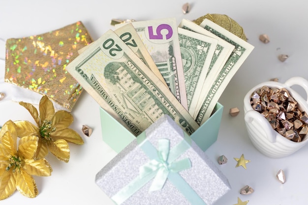 Dollar bills in a gift box as a christmas present next to christmas accessories and a protective face mask