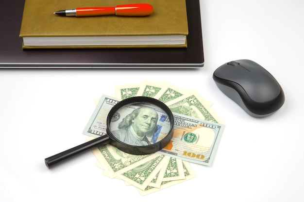 Dollar money on the background of a laptop and a magnifying glass Online business sale Financial business success