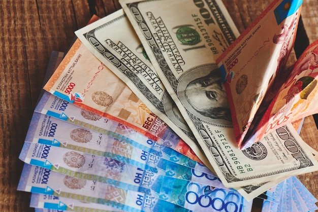 Dollars and tenge on a wooden background. Kazakhstan currency. Business and money.