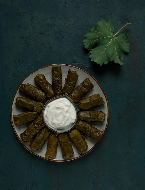 Dolma cabbage rolls in grape leaves Traditional Armenian dish with white sauce top view closeup selective focus