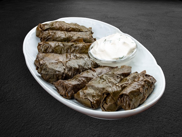 Dolma with lamb and white sauce Grape leaves with minced meat Oriental cuisine Isolated on a dark