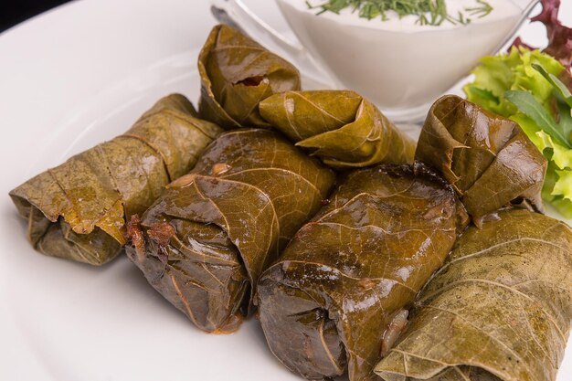 Dolma with meat and sour cream on a white plate