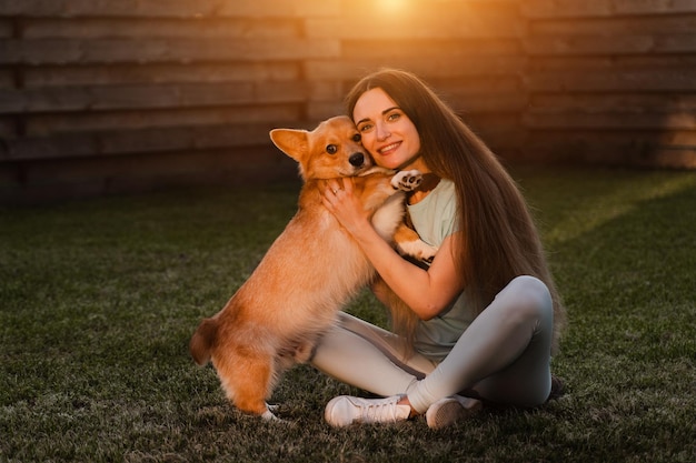 Domestic Corgi dog with girl owner Young woman sitting on the grass and hug Welsh Corgi Pembroke Lifestyle with domestic playful dog