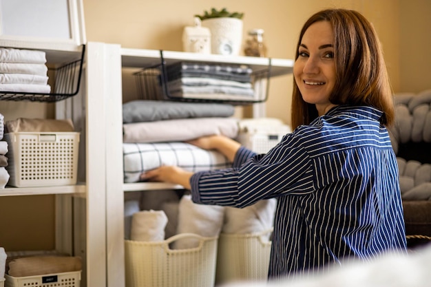 Domestic woman in pajamas neatly putting folded linens into cupboard vertical storage marie kondo