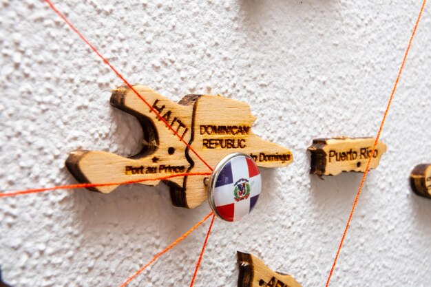 Photo dominican republic flag on the pin with red thread showed the paths on the wooden map