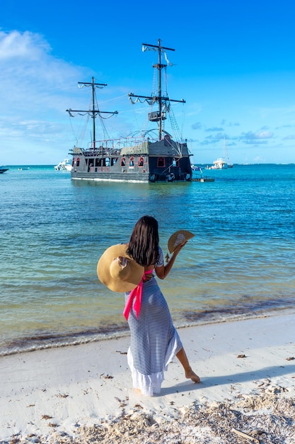 Dominican Republic of Punta Cana a girl in a hat on the ocean with turquoise water and palm trees