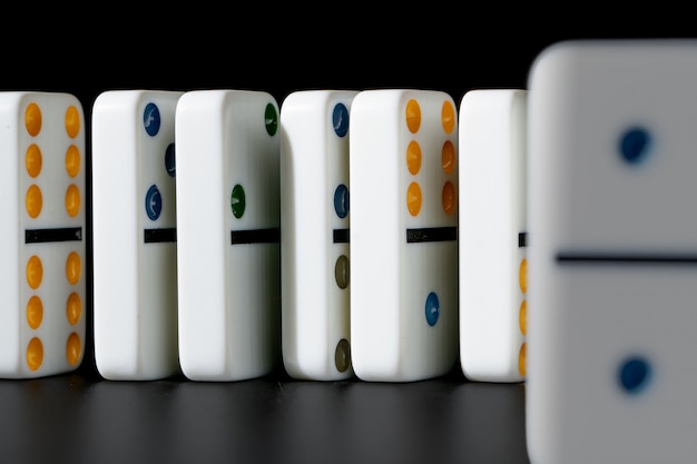 Dominoes standing in a row on black background