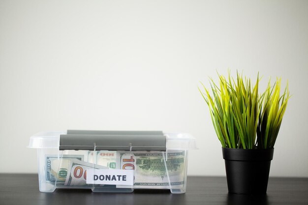 Donate box with dollars on wood desk