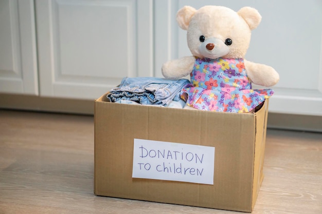 The donation box for clothes for children is not on the floor. Toys and baby stuff in the box. Donation and charity concept