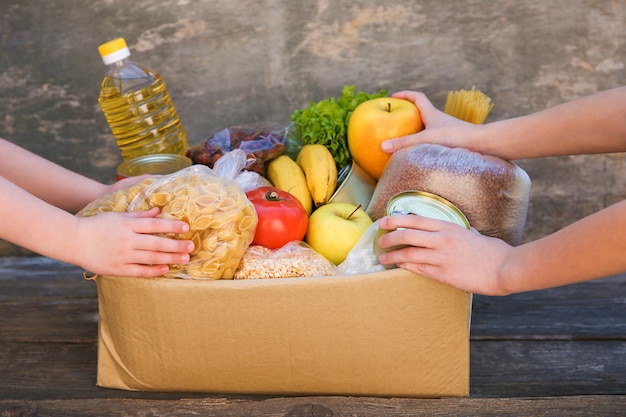 Donation box with food on old wooden background.