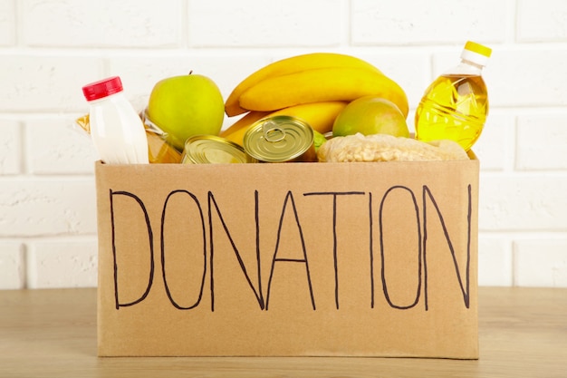 Donation box with food on the white brick wall