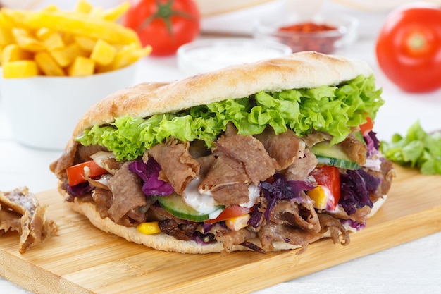 Doner Kebab Doner Kebap fast food meal in flatbread with fries on a wooden board