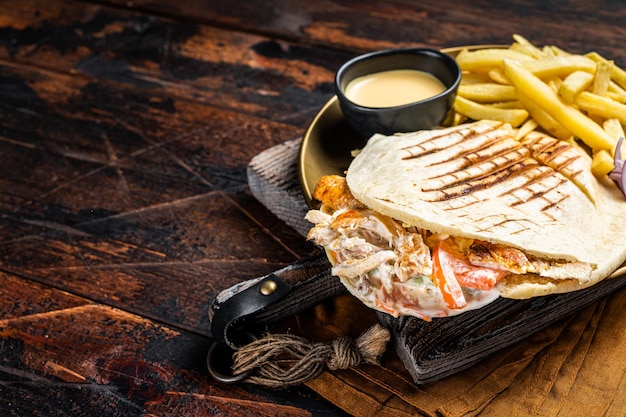 Doner kebab Shawarma in grilled pita bread with vegetables meat and french fry Wooden background Top view Copy space