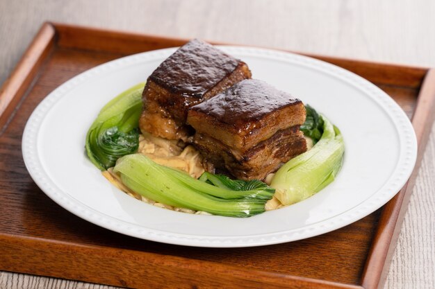 Dong Po Rou (Dongpo pork meat) in a beautiful blue plate with green broccoli vegetable, traditional festive food.