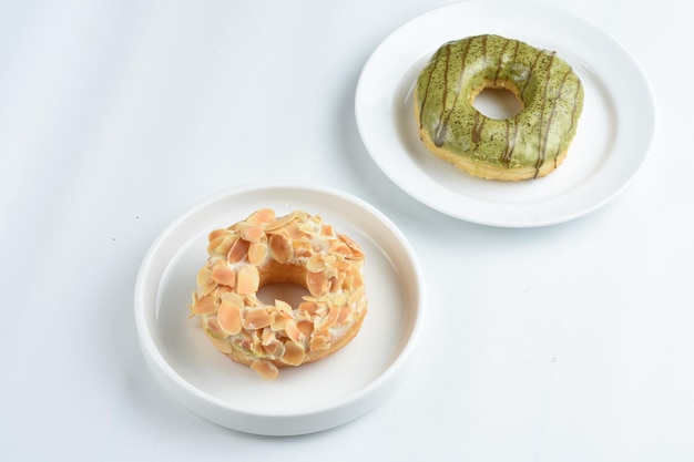 donut in white plate topped with green tea and almond slicesisolated on white background