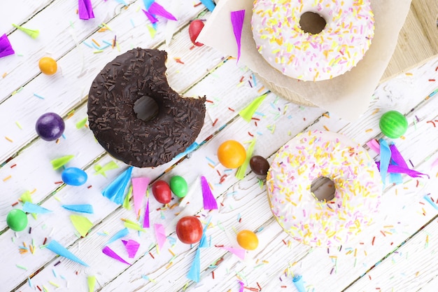 Donut on a wooden white background and a scattering of sweet ornaments