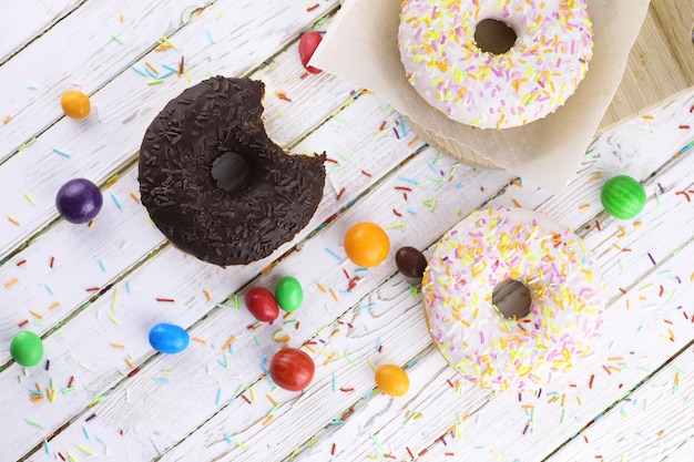 Donut on a wooden white background and a scattering of sweet ornaments