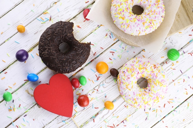 Donut on a wooden white background and a scattering of sweet ornaments