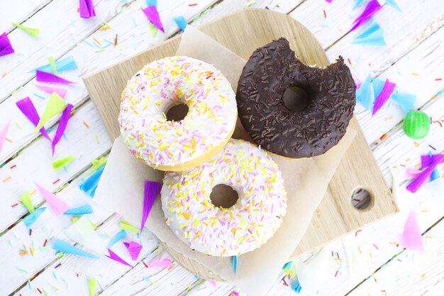 Donut on a wooden white background and a scattering of sweet ornaments