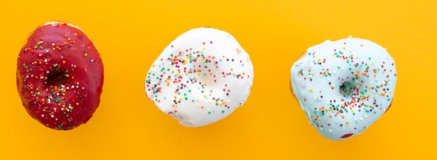 Donuts set isolated on a yellow background Cute colorful and glossy donuts with glaze and powder