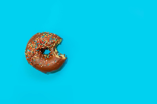 Donuts with chocolate glaze and colored sprinkles of round shape on a colored background