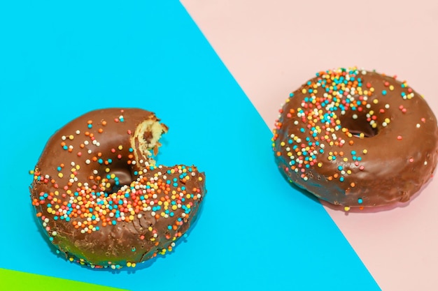 Donuts with chocolate glaze and colored sprinkles of round shape on a colored background