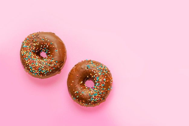 Donuts with chocolate glaze and colored sprinkles of round shape on a colored background