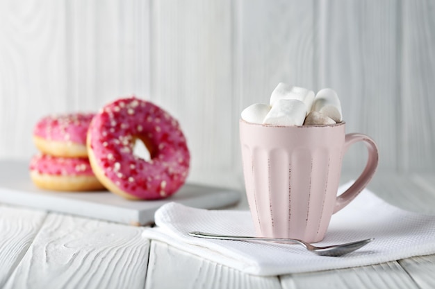 Donuts with pink glaze and colored caramel powder and cocoa with marshmallows