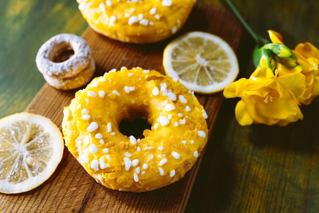 Donuts with sugar glaze and lemon on a wooden background.