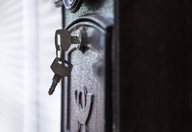 Door key inserted in keyhole ready to open black metallic mail box