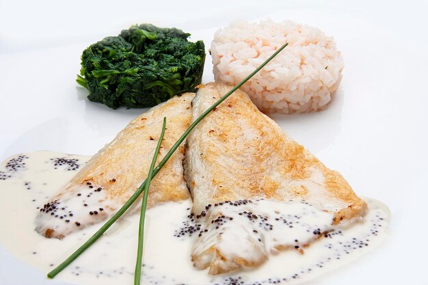 Dorado fillet with spinach and rice on a white background