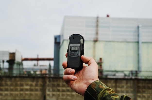 Photo dosimeter at hand and nuclear power plant on the background