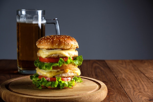 Double burger with cheese, salad, cutlets and glass of beer on wooden background