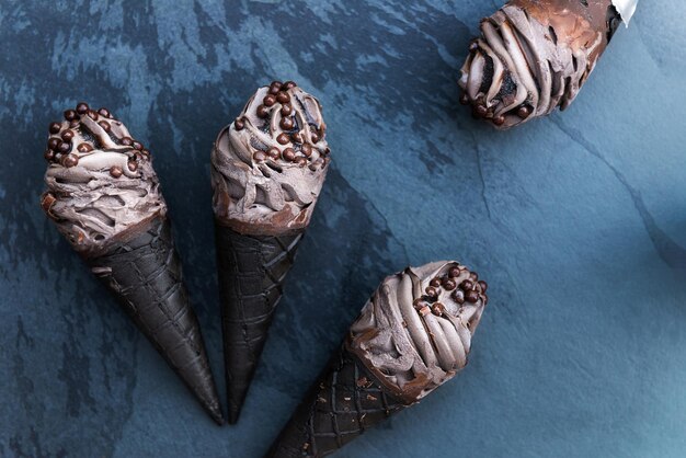 Photo double chocolate ice creams with black waffle cones on dark background