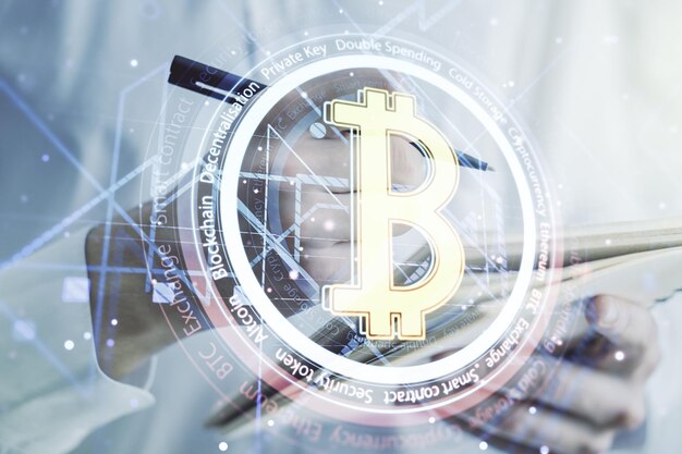 Double exposure of creative Bitcoin symbol with man hand writing in notebook on background Cryptocurrency concept