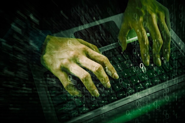 Double exposure of hacker hands using a laptop