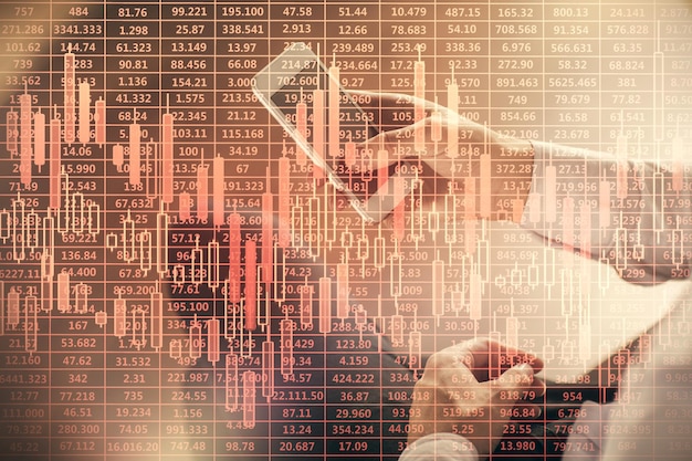 Double exposure of man's hands holding and using a digital device and forex graph drawing Financial market concept