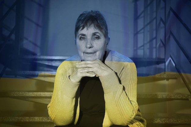 Double exposure of national flag and senior woman sitting on stairs Stop war in Ukraine