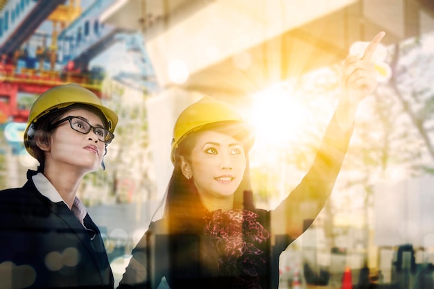 Double exposure of two female engineer discussing