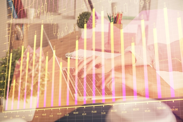 Double exposure of woman hands typing on computer and forex chart hologram drawing Stock market invest concept