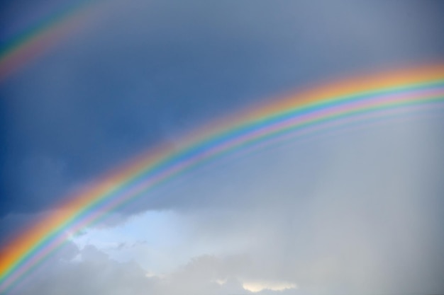 Double rainbow on a cloudy sky after rain Bright rainbow against the blue sky A rare atmospheric phenomenon after a heavy rain