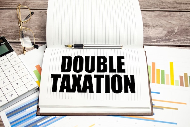 DOUBLE TAXATION text on notepad and calculator with charts