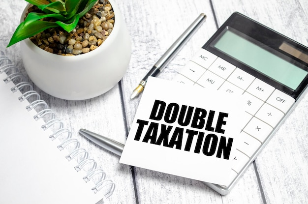 DOUBLE TAXATION word on white paper card and calculator