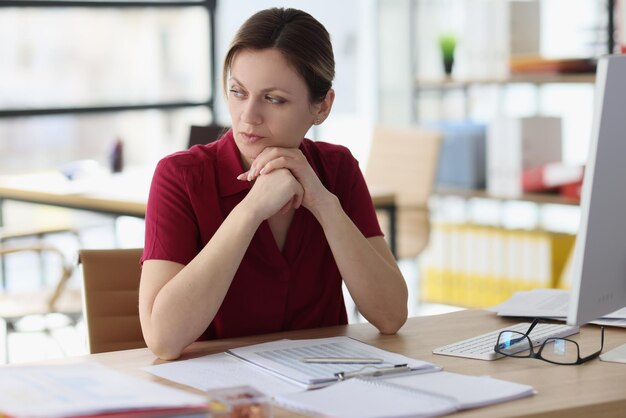 Doubting woman thinks about work looking away in office