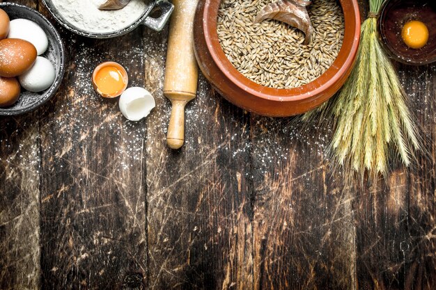 Dough background. Flour with wheat grains and fresh eggs.