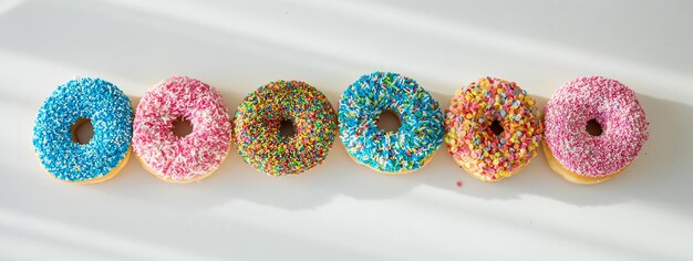 Doughnuts with colorful decoration on white color background Top view